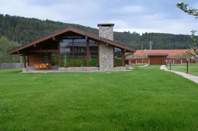a house with a large yard with a green lawn at Gostnici Holiday Home in Razlog