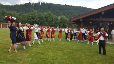 a group of people in traditional dances on the grass at Gostnici Holiday Home in Razlog