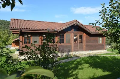a small wooden house with a grass yard at Gostnici Holiday Home in Razlog