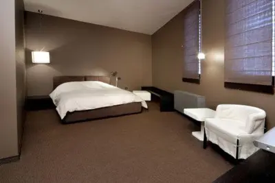 a bedroom with a bed and two white chairs at The Stone Villa in Beli Iskar