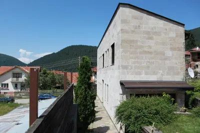 a brick building with a fence next to a street at The Stone Villa in Beli Iskar