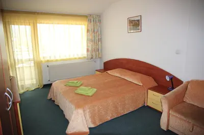 a bedroom with a bed with two green slippers on it at Hotel Grand in Samokov