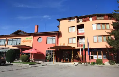 a large orange building with a restaurant in front of it at Hotel Grand in Samokov