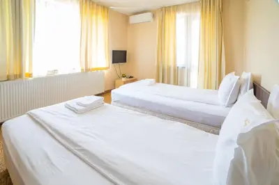 two beds in a hotel room with white sheets at Ring Hotel in Blagoevgrad