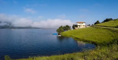 a house on a hill next to a body of water at Divna Forest & Lake House in Dospat