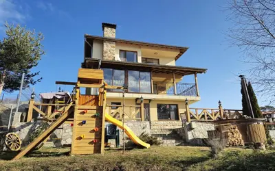a house with a slide in front of it at Divna Forest & Lake House in Dospat
