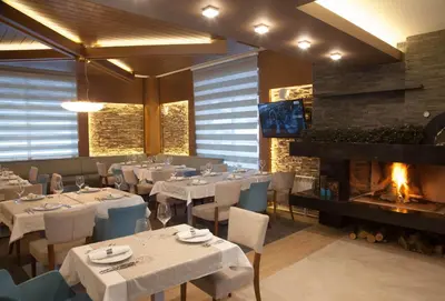 a restaurant with tables and chairs and a fireplace at Amira Boutique Hotel in Bansko