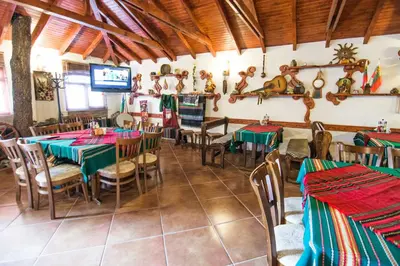 a restaurant with tables and chairs and a tv at Family Hotel Victoria Gold in Mineralni Bani