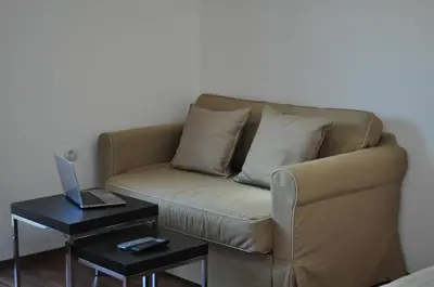 a couch with pillows and a laptop on a table at Apartment Elegant in Velingrad