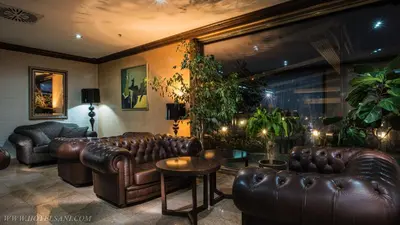 a living room with leather couches and plants at Hotel Sani in Asenovgrad