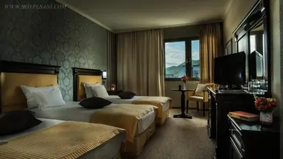 a hotel room with two beds and a television at Hotel Sani in Asenovgrad