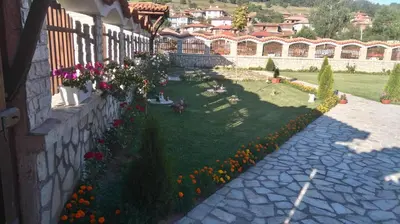a garden with flowers on the side of a building at Guest House H Dzhogolanov in Koprivshtitsa