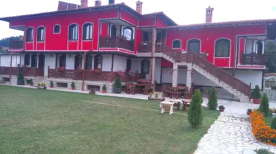 a large red building with stairs and a yard at Guest House H Dzhogolanov in Koprivshtitsa