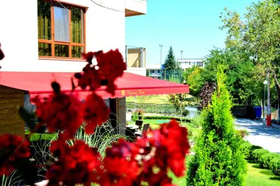 a garden with red flowers and a red umbrella at Victoriya's House in Hisarya