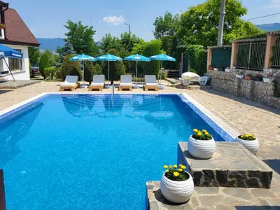 a swimming pool with chairs and umbrellas in a yard at Holiday House Kubrat in Sapareva Banya