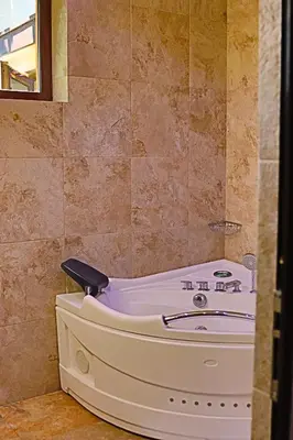 a bath tub in a bathroom with a tiled wall at Holiday House Kubrat in Sapareva Banya