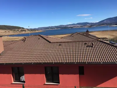 a red house with a roof and a body of water at La Casa Hotel in Tsigov Chark