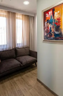 a couch in a living room with a painting on the wall at La Casa Hotel in Tsigov Chark