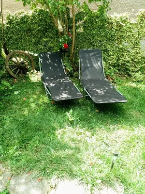 two black chairs sitting in the grass next to a wheel at Guest House Emiliya in Ovchartsi
