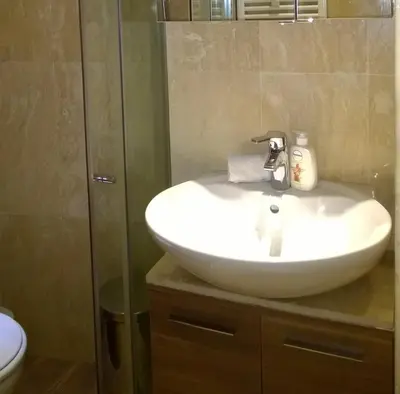a white sink in a bathroom with a shower at Parkview Apartments in Sofia