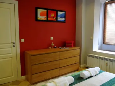 a bedroom with a dresser and a red wall at Parkview Apartments in Sofia