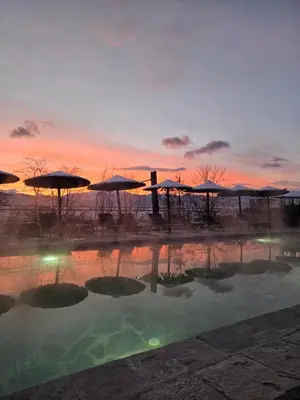 a sunset with umbrellas and a pool of water at Valentina Castle in Ognyanovo