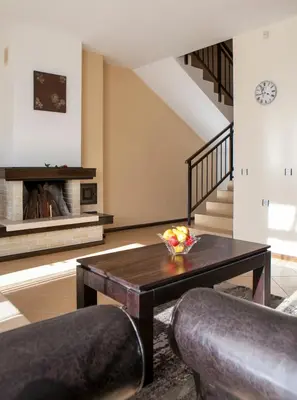 a living room with a table and a staircase at Къщи за гости КООП Добринище - Holiday Villages COOP Dobrinishte in Dobrinishte