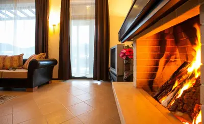 a living room with a fireplace and a couch at Къщи за гости КООП Добринище - Holiday Villages COOP Dobrinishte in Dobrinishte
