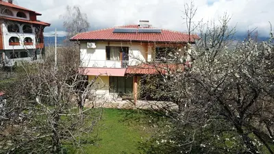 an old house with a red roof with a yard at Kot Garden Guest House in Sapareva Banya