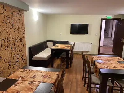a dining room with tables and chairs and a tv at Kot Garden Guest House in Sapareva Banya