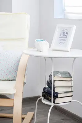 a white table with a stack of books next to a bed at Domus Apartments City Center with Parking in Plovdiv