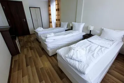 three beds in a hotel room with white sheets at Hotel Nikol in Dolna Banya