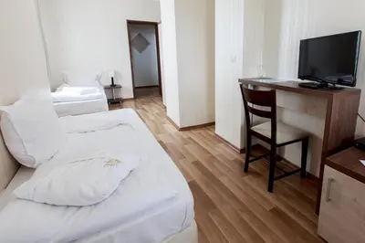 a room with two beds and a desk and a television at Hotel Nikol in Dolna Banya