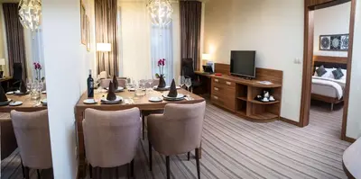 a hotel room with a dining table and a bedroom at Premier Sofia Airport Hotel in Sofia