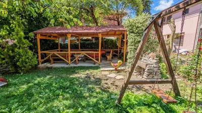 a wooden gazebo with a table and a swing at Pamir Guest House in Shipkovo