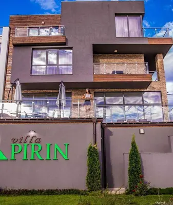 a woman standing on the balcony of a building at Villa Pirin in Simitli