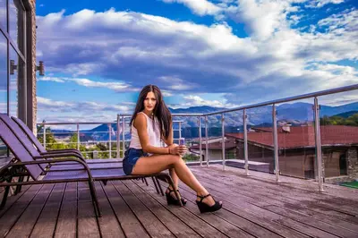 a woman sitting on a bench on a balcony at Villa Pirin in Simitli