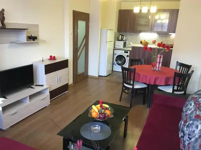 a living room with a table and a kitchen at Oscar Wilde Apartment in Sofia