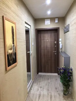 a hallway with a brown door and a vase of flowers at Oscar Wilde Apartment in Sofia