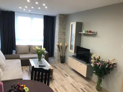 a living room with a couch and a tv and a table at Oscar Wilde Apartment in Sofia