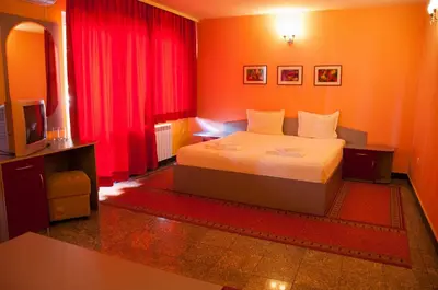 a hotel room with a bed and red curtains at Hotel Ertancom in Blagoevgrad
