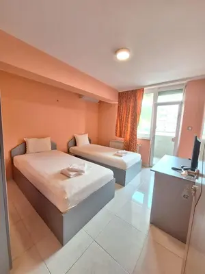 a room with two beds and a desk and a television at Hotel Ertancom in Blagoevgrad