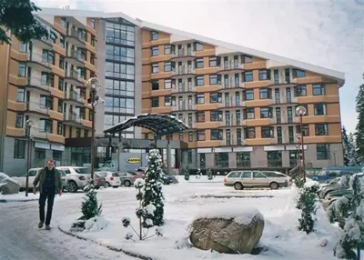 a man walking in the snow in front of a building at Flora Apartment 619 in Borovets