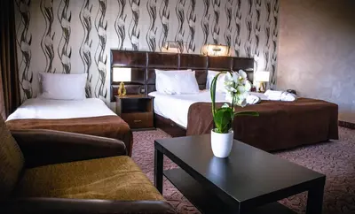 a hotel room with two beds and a couch and a table at Zdravets SPA Hotel in Velingrad
