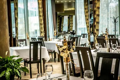a restaurant with white tables and chairs and windows at Zdravets SPA Hotel in Velingrad