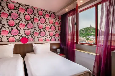 two beds in a room with a floral wall at Hotel Leipzig in Plovdiv