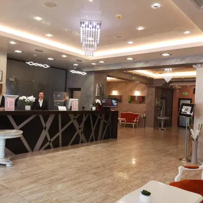 a woman standing at a counter in a lobby at Hotel Leipzig in Plovdiv