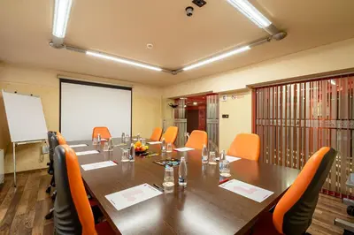 a conference room with a long table and orange chairs at Hotel Leipzig in Plovdiv