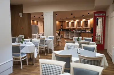 a restaurant with white tables and chairs and a kitchen at Hotel BLVD 7 in Plovdiv