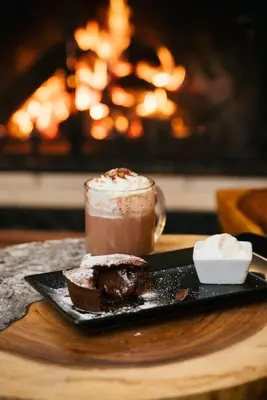 a chocolate dessert and a drink on a plate next to a fireplace at Green Life Bansko in Bansko
